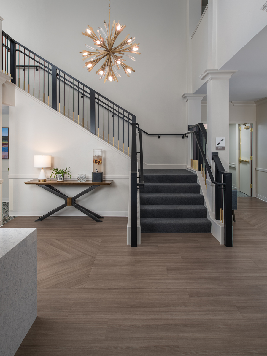 Two story lobby staircase at The Meadows with a chandelier and black railings